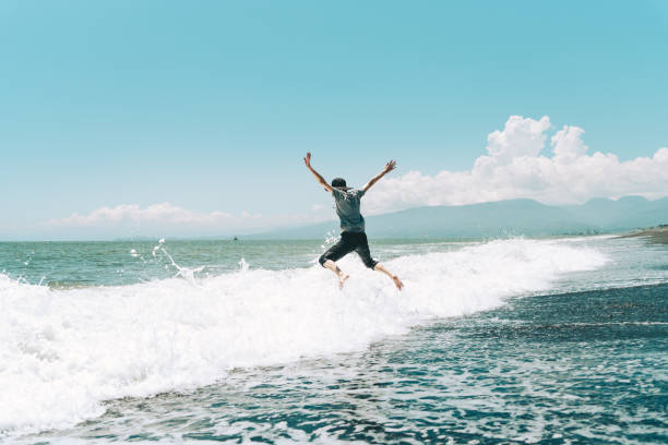 A woman jumping on the beach A woman jumping on the beach wave jumping stock pictures, royalty-free photos & images