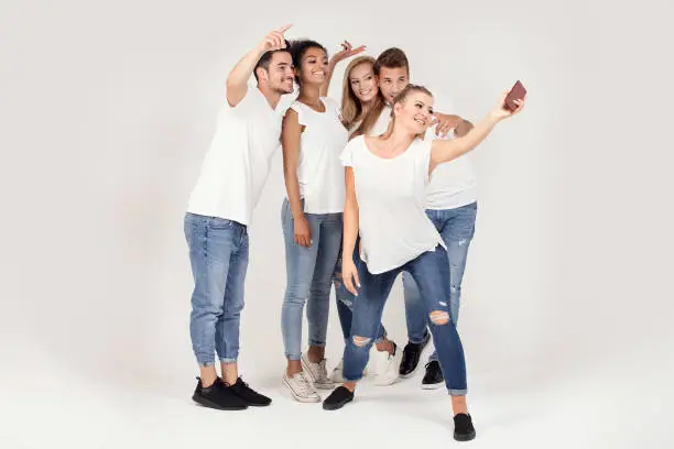 Group of young people enjoy their company, smiling, having fun together, taking selfie by mobile phone.