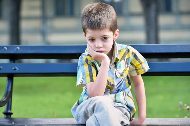 istock sad child boy sitting on a bench 1014107994