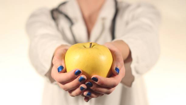 istock Female Doctor Holding Yellow Apple 1014108538
