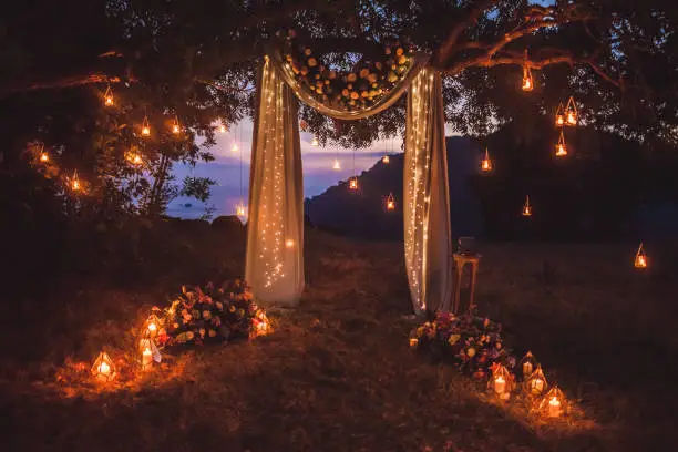 Photo of Night wedding ceremony with a lot of lights, candles, lanterns. Beautiful romantic shining decorations in twilight