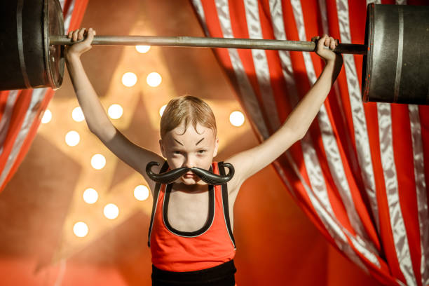 istock Amusing Boy Circus Strongman Holding Fake Barbell 1014121702