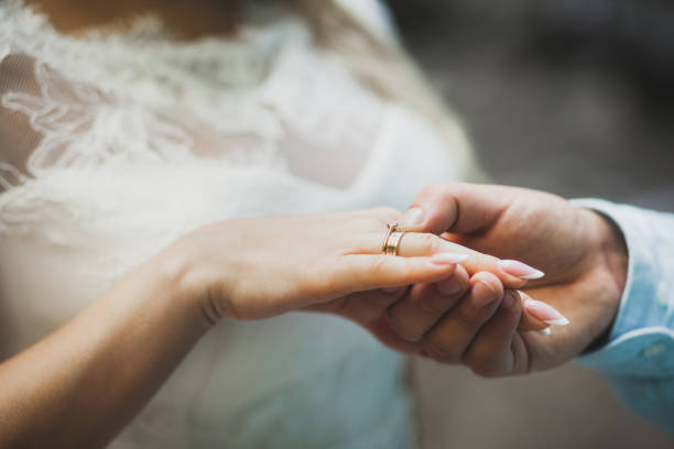 istock Groom wearing ring on bride's hand on wedding ceremony close-up 1014121746
