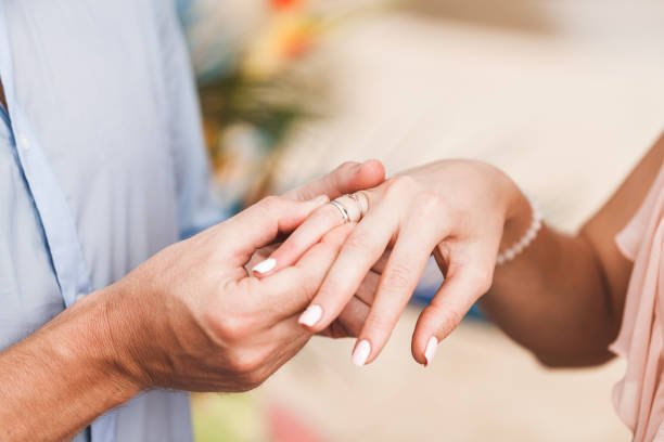 istock Groom wearing ring on bride's hand on wedding ceremony close-up 1014121750