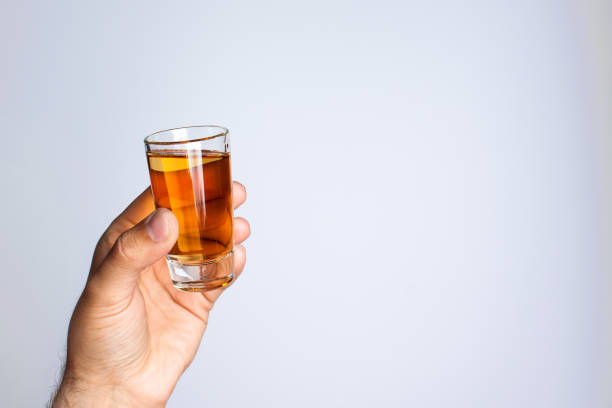 istock A man's hand holds a glass with liquid on a gray background 1014139706