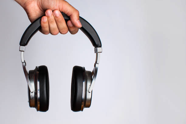 istock A man's hand holds a wireless headset on top of a gray background 1014139860