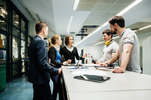 Team Of Engineers Holding Meeting In Factory A team of engineers holding a meeting in a large printing press factory. digital printing house stock pictures, royalty-free photos & images