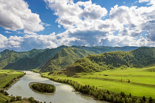 Río de montaña que fluye a lo largo de cañón, colinas de verde y cielo azul con nubes blancas photo