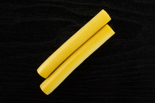 Group of two whole smoked slovak string cheese stick flatlay on black wood
