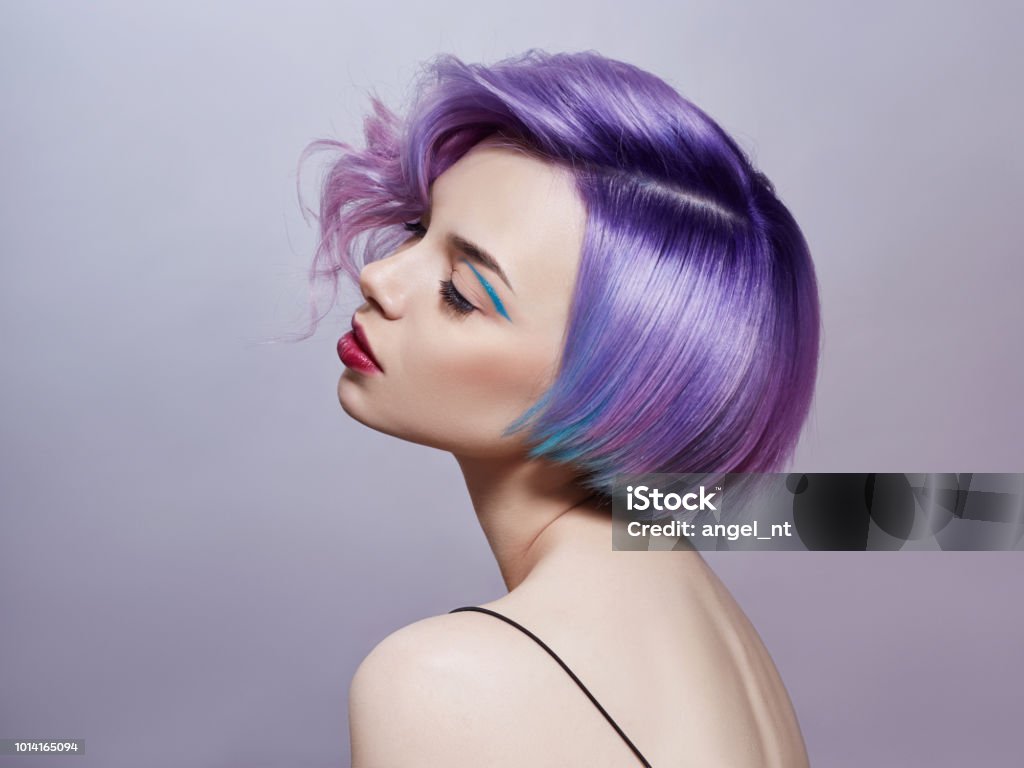 Portrait of a woman with bright colored flying hair, all shades of purple. Hair coloring, beautiful lips and makeup. Hair fluttering in the wind. Sexy girl with short  hair. Professional coloring Hair Stock Photo