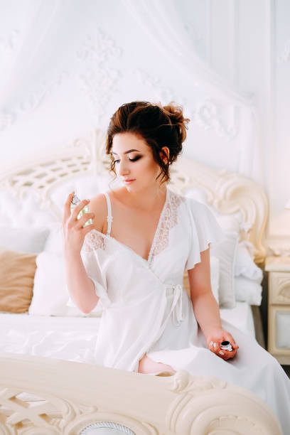 istock Sensual brunette in silk white robe waiting on the bed looking calm and relaxed 1014174426