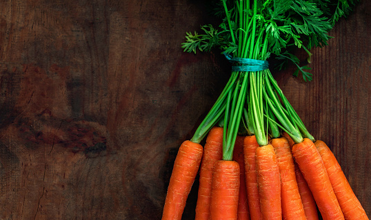 Fresh carrots bunch on rustic wooden background with copy space. Healthy  Detox concept