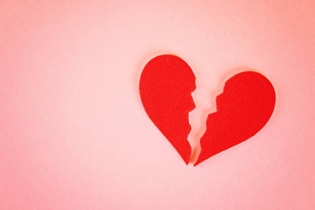 istock Red felt heart broken into two halves on a pink background. 1014179338