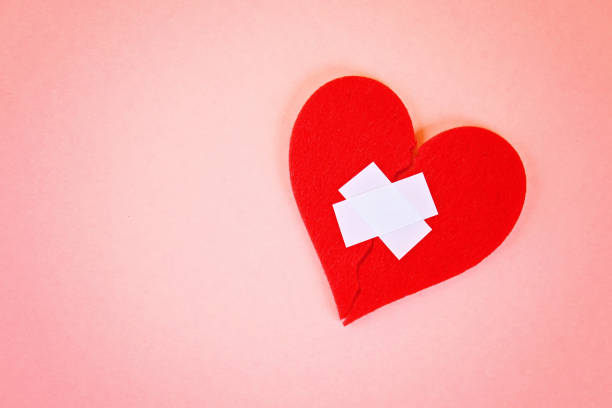 istock A red felt heart broken into two halves, glued together by a plaster on a pink background. 1014179380