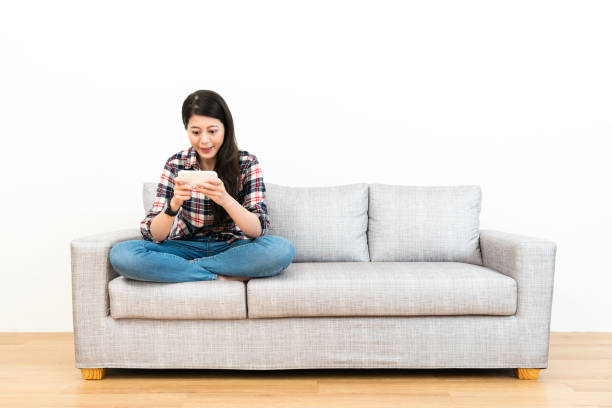istock girl sitting on sofa couch using mobile cell phone 1014179510