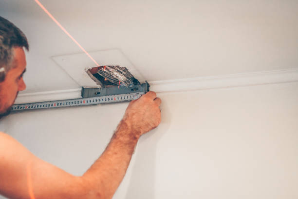 istock finishing work - working with a tape measure and a laser construction level marks a wall 1014181632