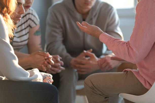 close-up of a therapist gesticulating while talking to a group of listing teenagers during an educational self-acceptance and motivation meeting. - grupo pequeno de pessoas imagens e fotografias de stock