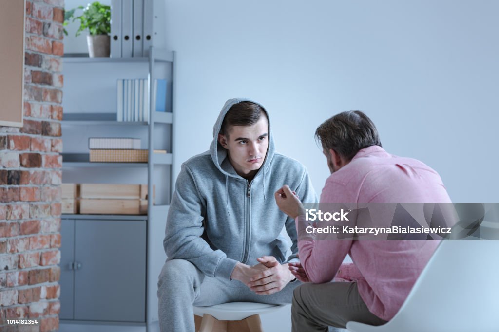 A psychology specialist explaining an action plan for recovery to a troubled teenage boy during an individual therapy session. Addiction Stock Photo