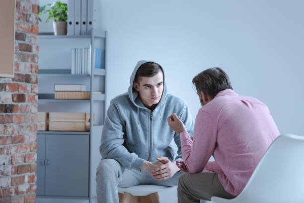 a psychology specialist explaining an action plan for recovery to a troubled teenage boy during an individual therapy session. - addiction imagens e fotografias de stock