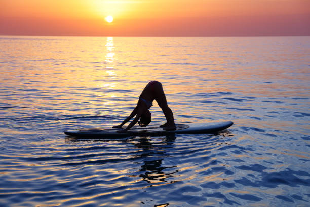 Sportive female doing yoga exercise on the beach stock photo
