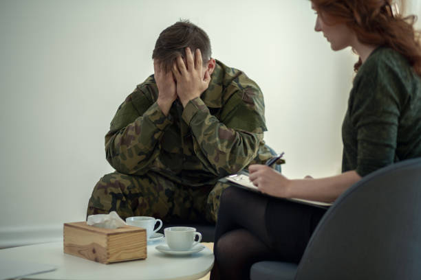 istock Soldier hiding his face in his hands while talking to a psychiatrist during therapy 1014213018