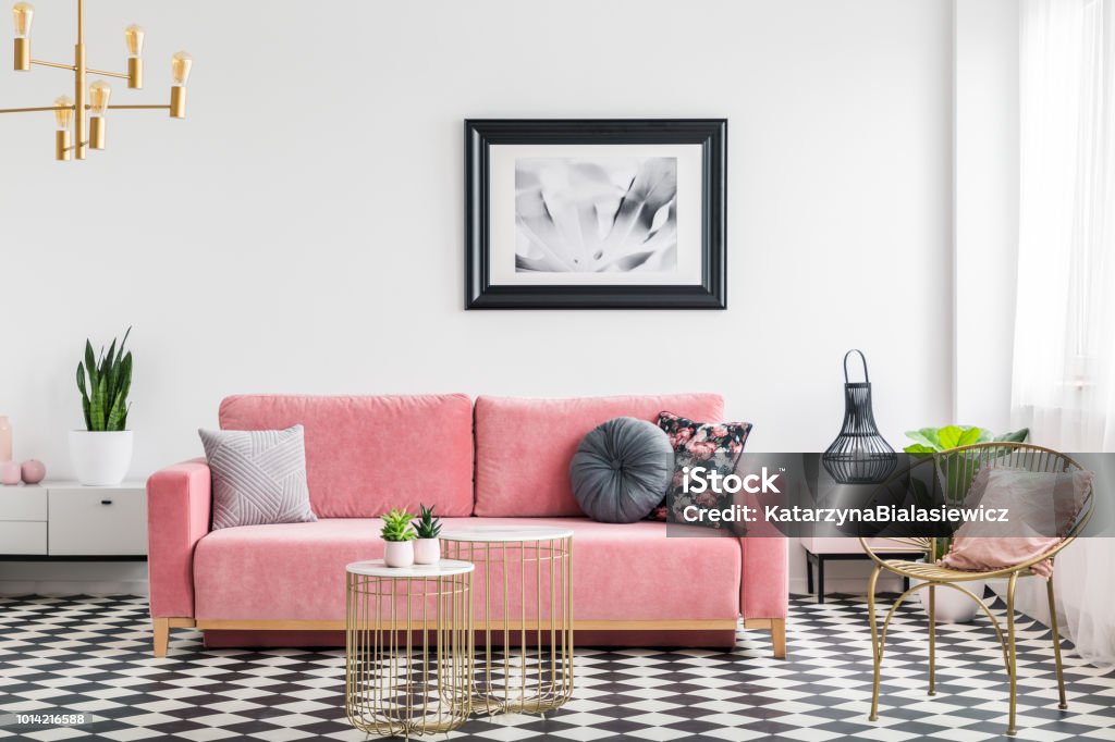 La vie glamour room intérieure avec un canapé rose, fauteuil doré et tableaux, peinture et damier carreaux. Vraie photo - Photo de Salon - Pièce libre de droits