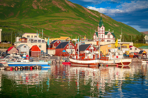 Scenic view of the historic town of Husavik in beautiful golden evening light at sunset with blue sky and clouds, north coast of Iceland