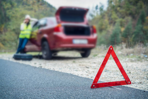 istock Woman talking on the phone while changing car tire 1014225370