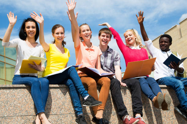 istock Excited students with arms outstretched outdoors 1014228108