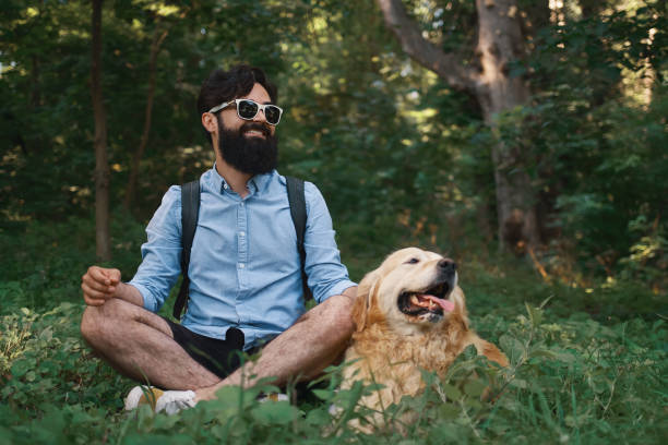 istock Man resting on the grass sitting crossed legs with his dog 1014228616