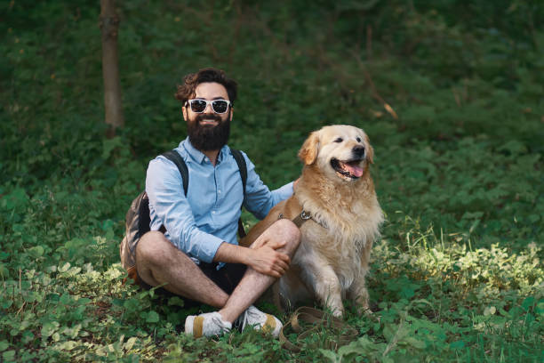istock Man resting on the grass sitting crossed legs with his dog 1014228754
