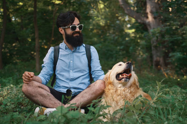 istock Man resting on the grass sitting crossed legs with his dog 1014228804