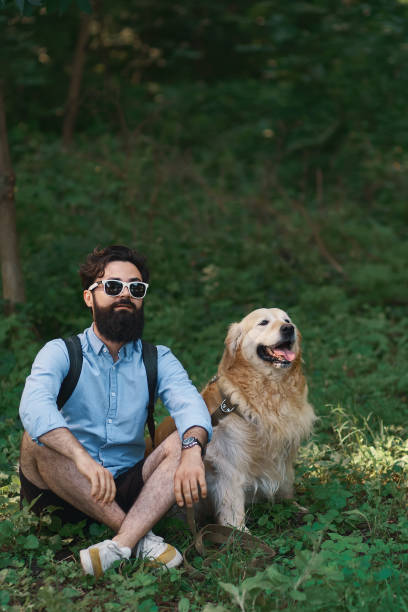 istock Man resting on the grass sitting crossed legs with his dog 1014228832