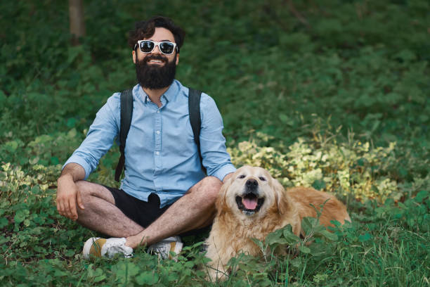 istock Man resting on the grass sitting crossed legs with his dog 1014228850
