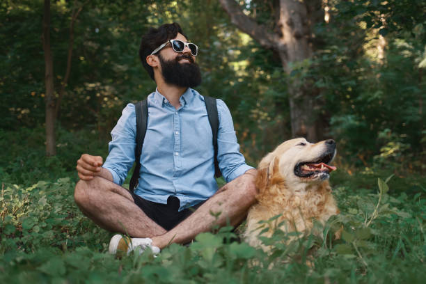 istock Man resting on the grass sitting crossed legs with his dog 1014228864