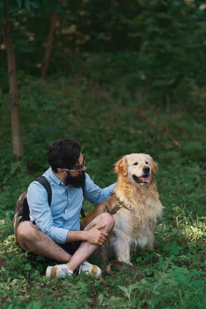 Man resting on the grass sitting crossed legs with his dog