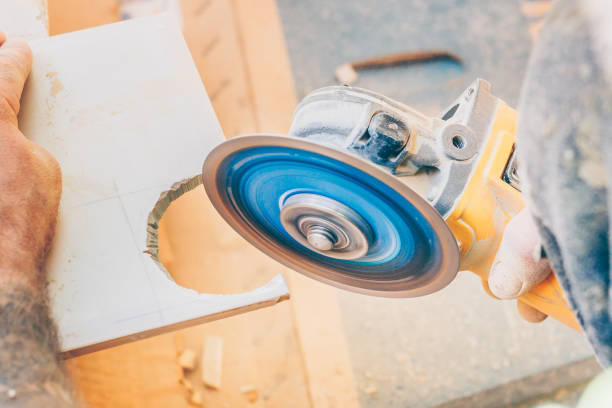 istock Finishing works - the tiler cuts a round hole in the tile with an angle grinder 1014245536