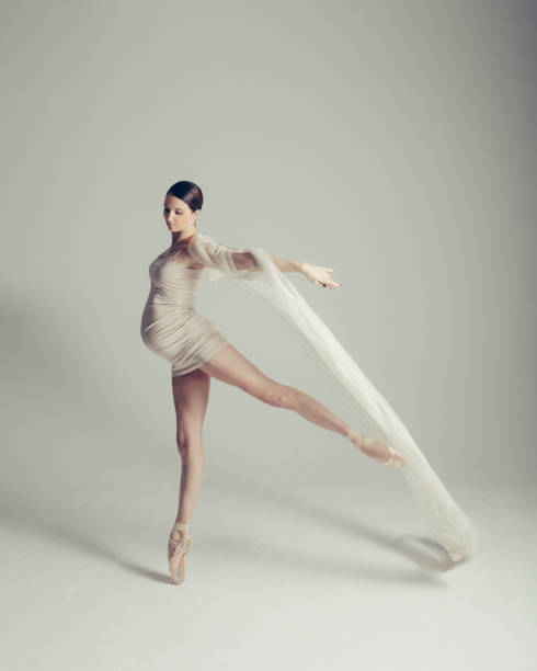 Young beautiful pregnant ballerina is posing in studio