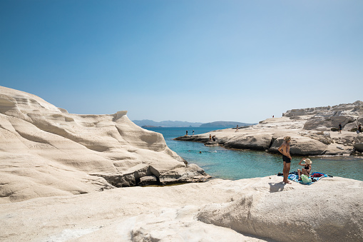 Milos island, Greece - June 09, 2018: Tourists enjoying their vacations on a beautiful white rock formations in Sarakiniko beach which is situated on the north shore of the island.