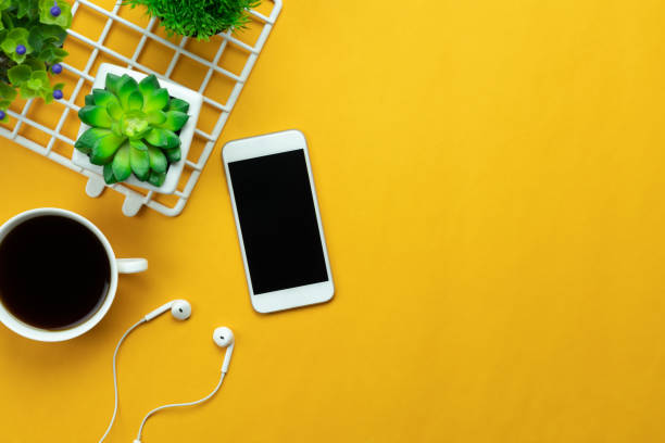 table top view aerial image of accessories office desk background concept.flat lay of variety object the white mobile phone & tree pot and coffee with earphone on modern rustic yellow paper and space. - wooden pattern audio imagens e fotografias de stock