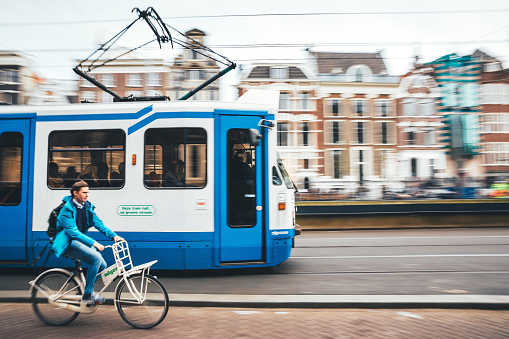 Amsterdam, Netherlands - April 17, 2018: Street scene from Amsterdam (near central station) with moving tram and cyclist riding by. Motion blurred.