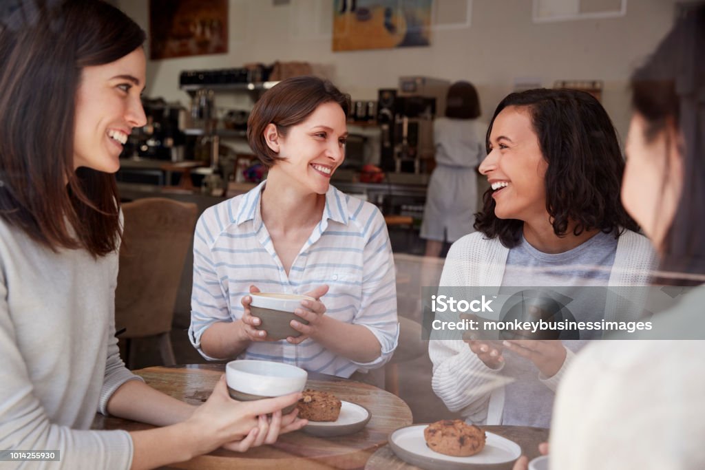 Quatre amies détente autour d’un café dans une cafétéria - Photo de Femmes libre de droits