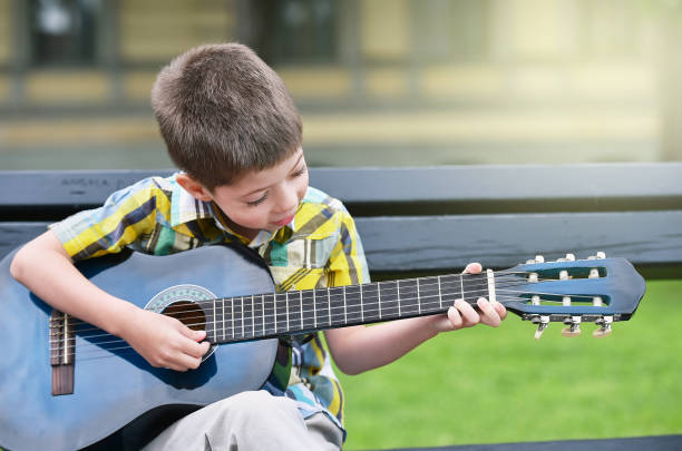 istock child boy playing on guitar in a park 1014259450