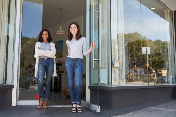 zwei junge weibliche coffee-shop-besitzer stehen vor ihrem laden - women customer service representative service standing stock-fotos und bilder