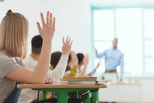 istock high school students raising hands to answer teachers question 1014266126