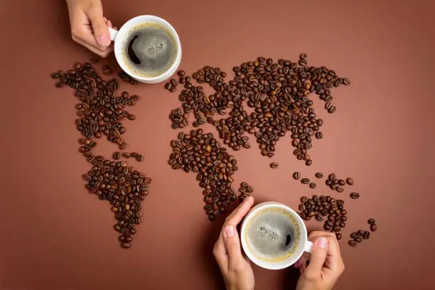 Map of the world made of roasted coffee beans on brown paper background. International coffee industry or travel planning concept