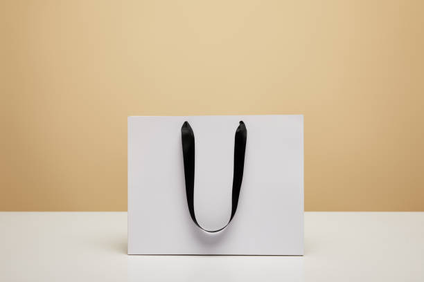 istock one white shopping bag on white tabletop isolated on beige 1014276412