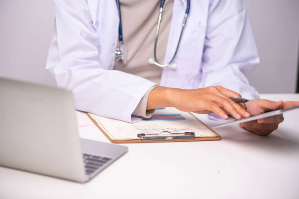istock Doctor working with laptop computer and writing on paperwork. Hospital background. 1014291822