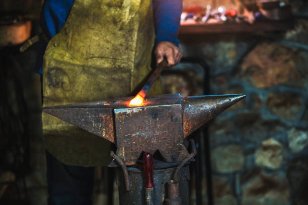 istock Blacksmith manually forging the molten metal on the anvil in smithy with spark fireworks, close up 1014291946