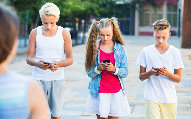 istock Three children keened on mobile phones during joint walk around city 1014297534